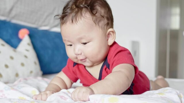Close up shot of an asian baby girl,  moving backwards as she tries to crawl for the first time.