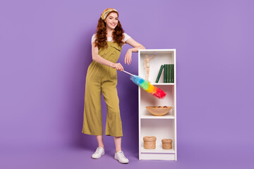 Full length body size view of pretty cheerful girl making order on shelves isolated over violet purple color background