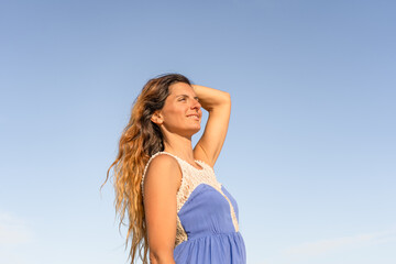 Fototapeta na wymiar Portrait of smiling beautiful young female enjoying sunny day with blue sky.
