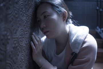 young beautiful Asian woman in pain suffering depression - dramatic indoors portrait on staircase of sad and depressed Chinese girl as victim of bullying and abuse