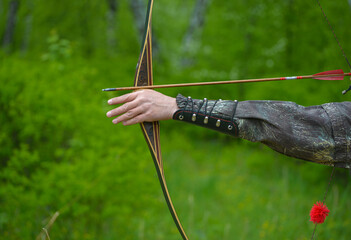 professional archers shooting with modern longbows at meadow