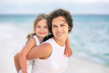 Portrait of happy mother and little daughter on ocean beach on Maldives at summer vacation. Family...