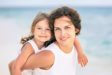 Portrait of happy mother and little daughter on ocean beach on Maldives at summer vacation. Family on the beach concept.