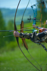 professional archers shooting with modern longbows at meadow