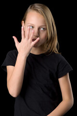 Close up portrait of teenage girl in black t-shirt gesturing against black background.