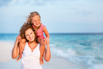 Fototapeta na wymiar Happy mother and little daughter having fun on beach on Maldives at summer vacation. Family on the beach concept.