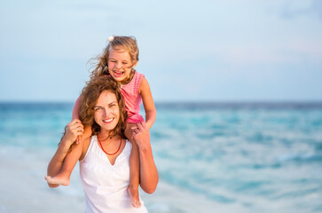 Fototapeta na wymiar Happy mother and little daughter having fun on beach on Maldives at summer vacation. Family on the beach concept.