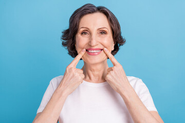 Photo portrait woman smiling showing finger pointing white teeth veneers isolated pastel blue color background