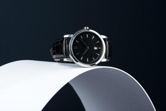 Luxury men's watch on a curved white surface and dark background