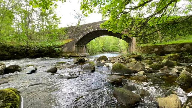 Stream flowing under an old Stone bridge in Ireland's countryside