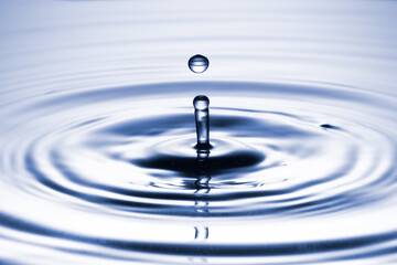 Water drop separating from a clean, blue surface