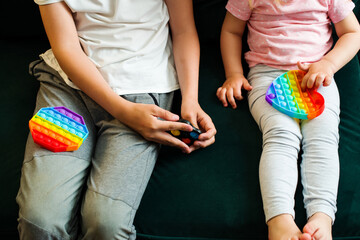 Anti-stress rainbow pop it fidget toy in children's hands. Push bubble fidget sensory toy, use a fine motor game, help restore emotions - obrazy, fototapety, plakaty