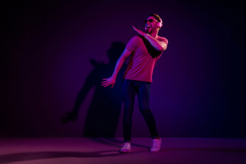 Full length body size view of attractive funny cheerful guy listening hit sound dancing isolated over dark neon violet color background