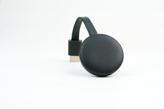 Chromecast media streaming player device on white background. Selective focus.