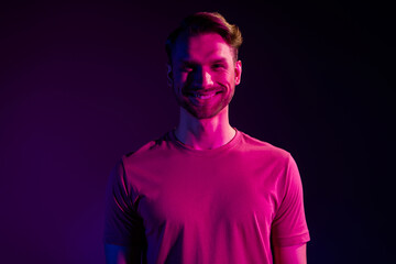 Portrait of attractive cheerful content guy at night club isolated over dark neon light violet color background
