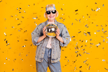 Photo portrait of senior woman wearing sunglass keeping disco ball at party with sequins isolated...