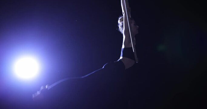 Woman circus artist make a show on a stage hanging on a ring, slow motion