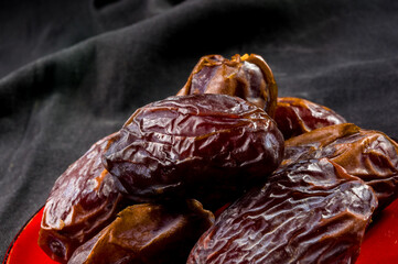 Big luxury dried date fruit in bowls on the dark surface, kurma ramadan kareem concept, close up.
