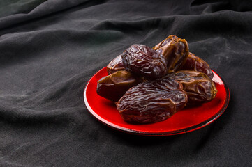 Big luxury dried date fruit in bowls on the dark surface, kurma ramadan kareem concept, close up.