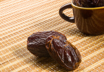 Big luxury dried date fruit on the bamboo mat, kurma ramadan kareem concept, close up.