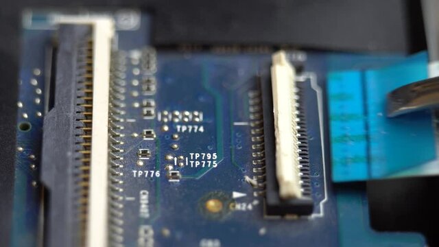 Connecting a flex cable to the laptop motherboard with tweezers, laptop repair in a service center