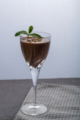 Chocolate cocktail with nuts and mint in a glass on a black background.