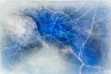 Aerial view of abstract patterns formed by snow and cracks within a blue and white frozen ice sheet