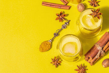Obraz na płótnie Canvas Golden turmeric milk with ice on bright yellow background