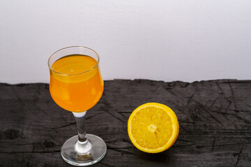 Orange juice in a glass near oranges on a black background.