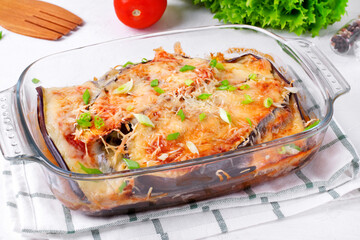 Vegetarian casserole with eggplant, parmigiano cheese and tomato sauce in the glass baking dish
