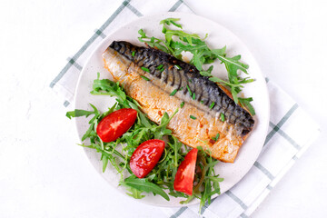 Roasted mackerel served with arugula and tomatoes. Fish meal. Top view