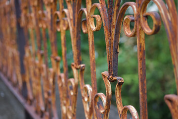 old rusty wrought iron railing,coating was peeling off. background blurred green nature (selective...