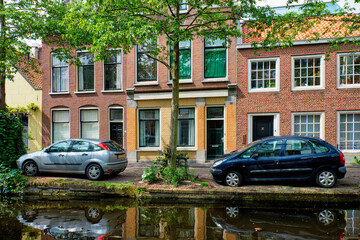 Fototapeta na wymiar Cars on canal embankment in street of Delft. Delft, Netherlands