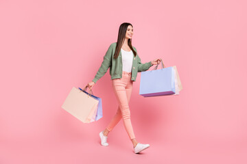 Full size photo of optimistic girl go with bags wear sweater trousers sneakers isolated on pink color background