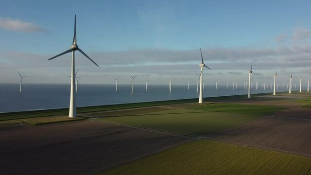Wind turbines on a levee and off shore wind turbines off the coast of Flevoland in the IJsselmeer in The Netherlands. Aerial view.