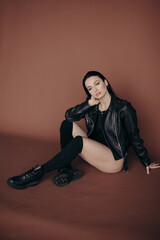 girl in a black leather jacket on a brown background, shooting in the studio