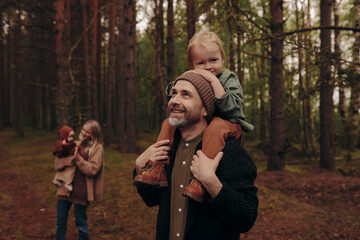 Happy family with children walking in the park.
Man giving young girl piggyback ride outdoors