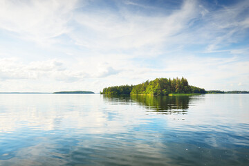 Rocky lakeshore and forest on a sunny summer day. Green trees, plants. Bålsta, Mälaren lake, Sweden. Idyllic landscape. Reflections on water. Nature, ecology, environment, ecotourism, hiking