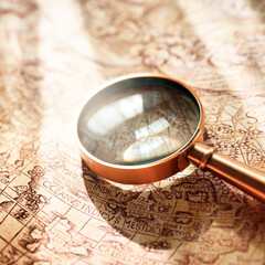 Retro copper colored magnifying glass and old white nautical chart close-up. Vintage still life....