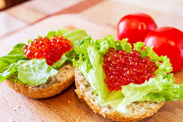 On the bun is a lettuce leaf and red caviar close-up.