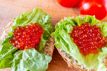 On the bun is a lettuce leaf and red caviar close-up.