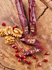 slicing Churchkhela, pomegranate and nuts on a wooden background, top view, serving