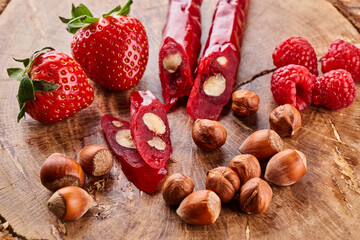 slicing Churchkhela, strawberries and nuts on a wooden background, top view, serving