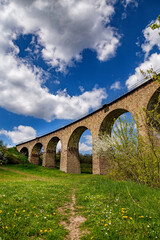 Fototapeta na wymiar Old railway stone viaduct in the spring in sunny day.