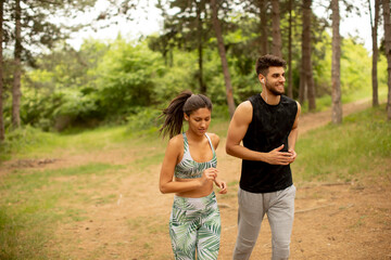 Young fitness couple running at the forest trail