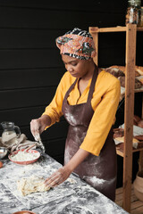 African young baker in apron kneading the dough and baking homemade bread