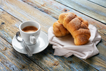 View from above. Cup of hot Italian espresso coffee and croissants on a light blue rustic wooden background. Food and drink. Lifestyle.