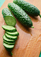 Set of fresh whole and sliced cucumbers on a wooden board with water drops. Garden cucumber wallpaper backdrop design