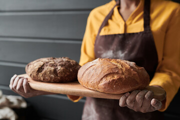 Close-up of baker holding tray with homemade fresh bread