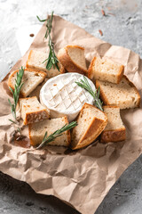 Baked camembert with toasts on rustic background